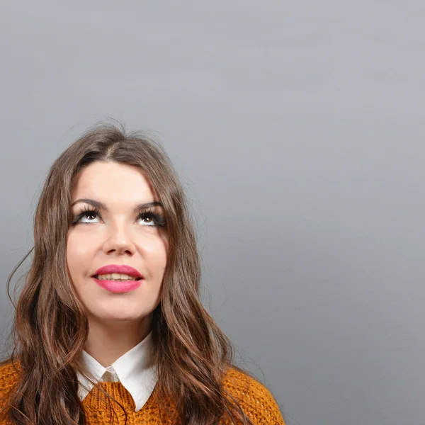 Mujer hermosa mirando el área en blanco contra el fondo gris — Foto de Stock