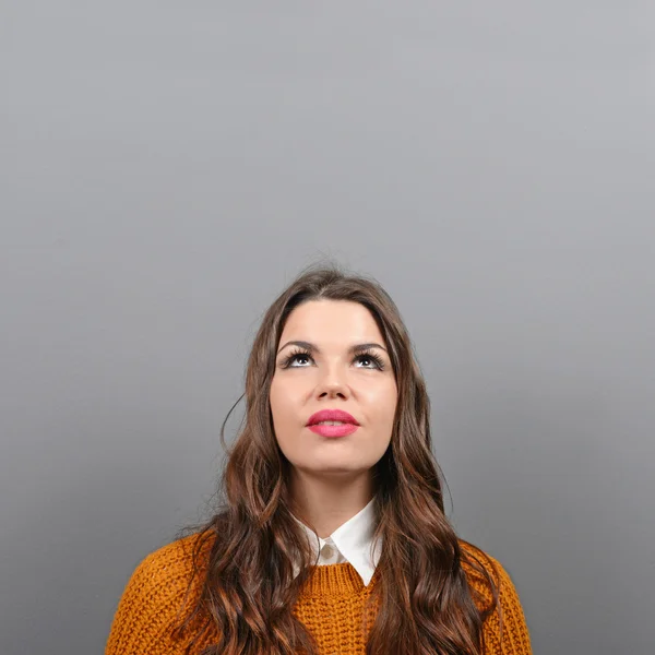 Mooie vrouw kijken naar leeg gebied tegen de grijze achtergrond — Stockfoto