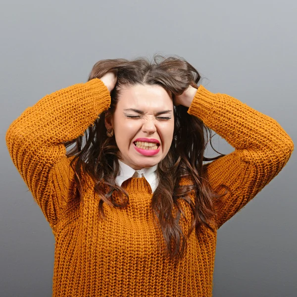 Portrait of a histerical woman pulling hair out against gray bac — Stock Photo, Image