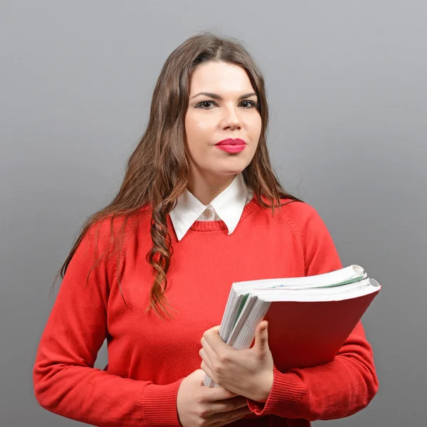 Portrait of happy student woman holding books against gray backg — Stock Photo, Image