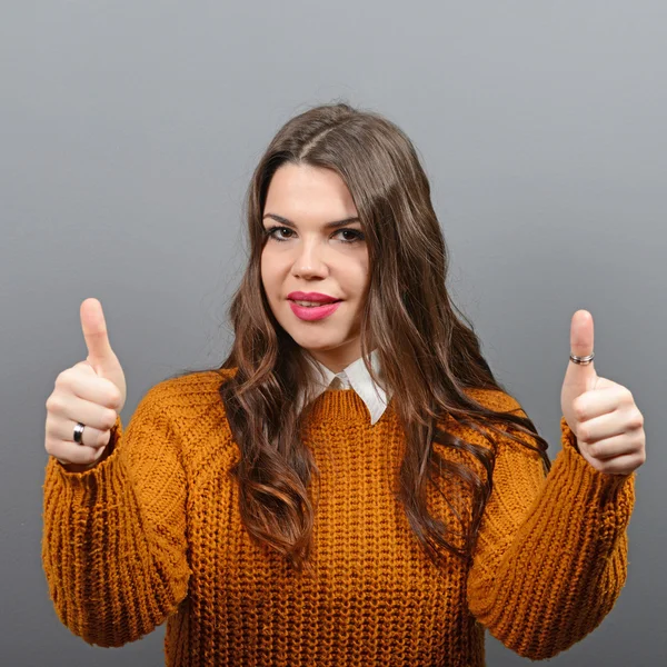 Retrato de mujer feliz sosteniendo pulgares contra fondo gris — Foto de Stock