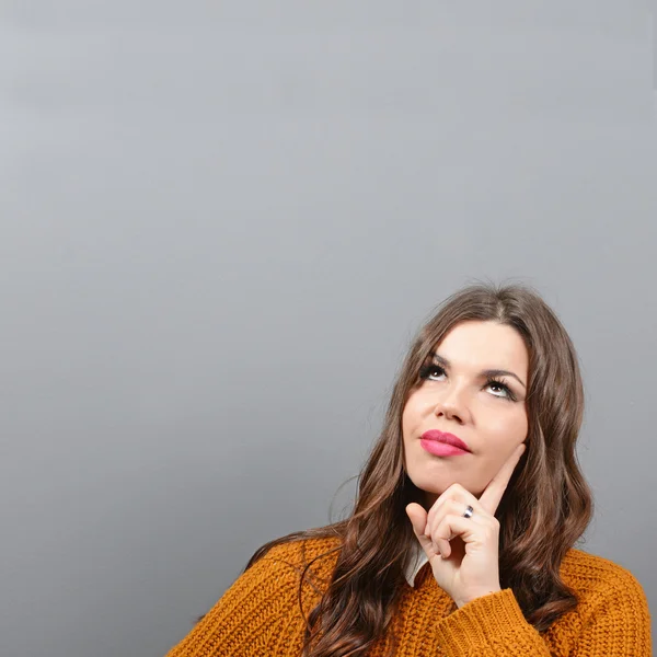 Portrait of thoughtful woman against gray background — Stock Photo, Image