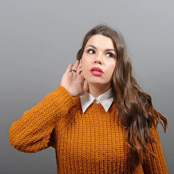 Portret van een vrouw wilt beluisteren iets tegen grijs backg — Stockfoto