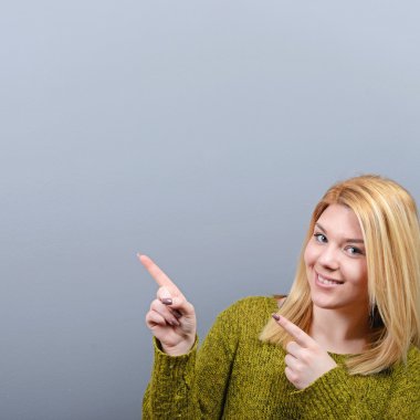 Gri arka plan boş alanı işaret eden güzel bir kadın