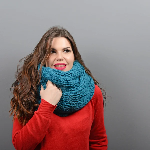 Portrait of young beautiful woman in winter clothes against gray