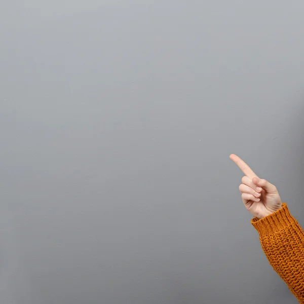 Frauenhand zeigt auf weiße Fläche vor grauem Hintergrund — Stockfoto