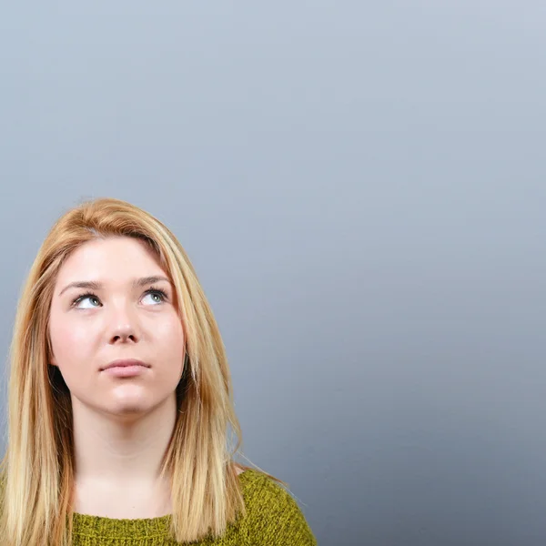 Mujer hermosa mirando el área en blanco contra el fondo gris — Foto de Stock