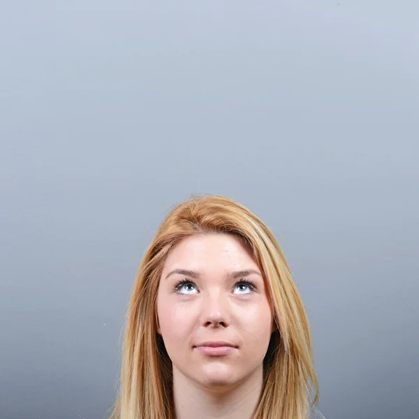 Mujer hermosa mirando el área en blanco contra el fondo gris — Foto de Stock