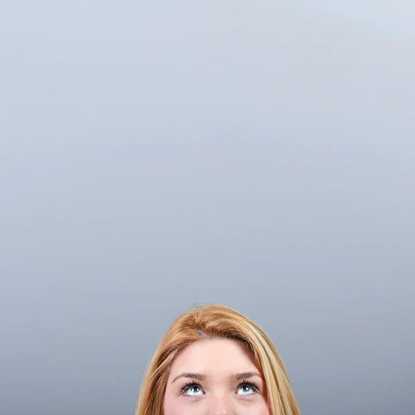 Mulher bonita olhando para a área em branco contra fundo cinza — Fotografia de Stock