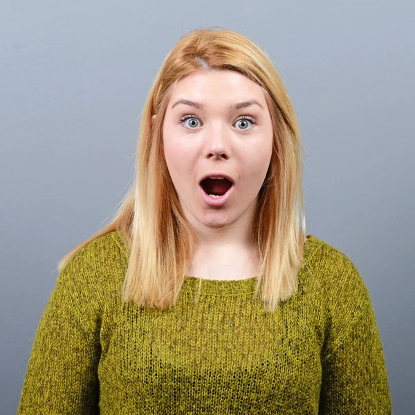 Portrait of a amazed woman against gray background — Stock Photo, Image