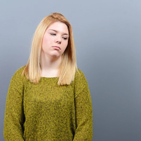 Portret van een trieste vrouw tegen de grijze achtergrond — Stockfoto