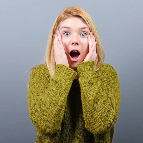 Portrait of a surprised woman against gray background — Stock Photo, Image