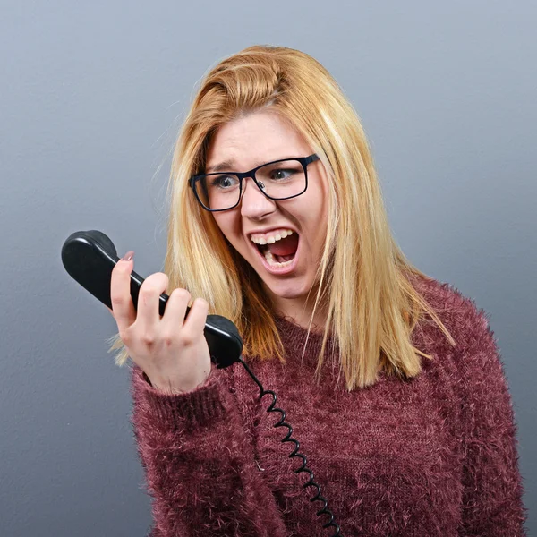 Portrait of a woman yelling at headhone against gray background — Stock Photo, Image