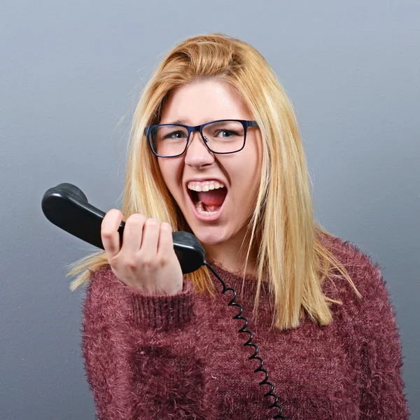Portrait of a woman yelling at headhone against gray background — Stock Photo, Image
