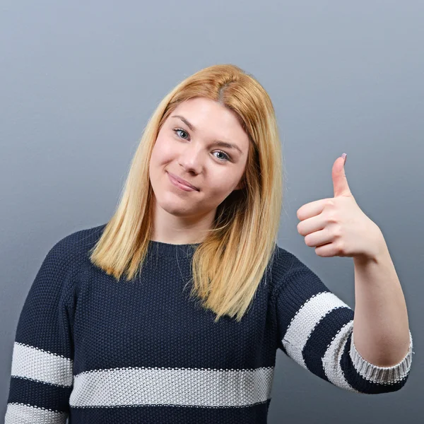 Portrait of happy woman holding thumbs up against gray backgroun — Stock Photo, Image