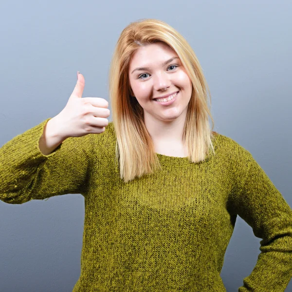 Retrato de mulher feliz, segurando os polegares contra background cinza — Fotografia de Stock