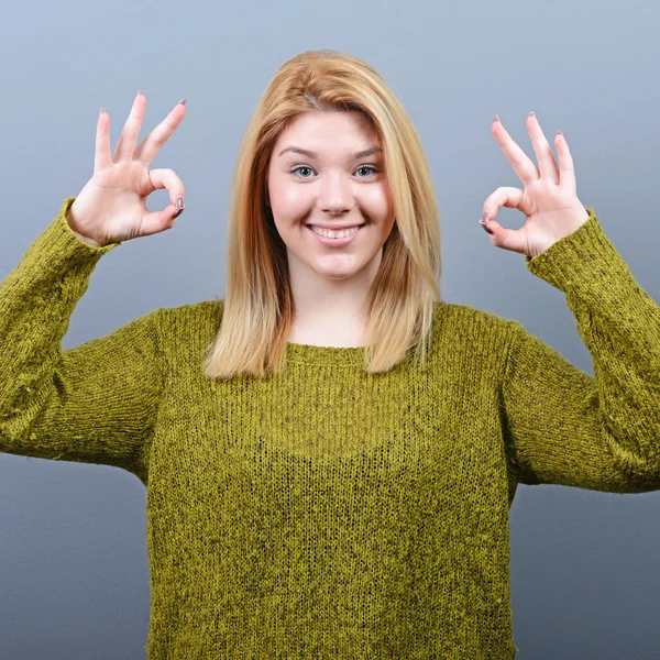 Retrato de mujer feliz mostrando signo de ok contra fondo gris — Foto de Stock