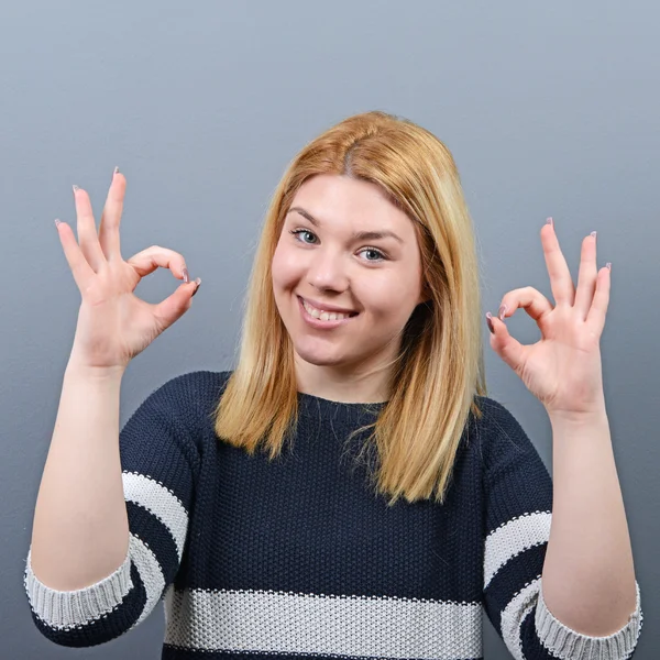 Retrato de mujer feliz mostrando signo de ok contra fondo gris — Foto de Stock