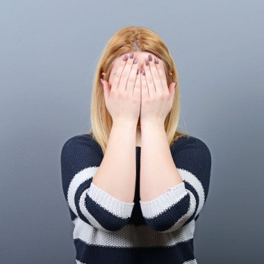 Gri b karşı iki elinizle yüzünü gizleme kadın portresi