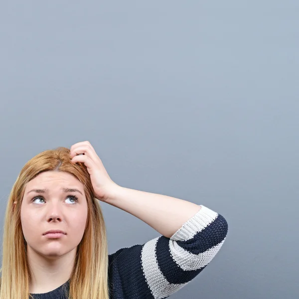 Porträt einer nachdenklichen Frau vor grauem Hintergrund — Stockfoto