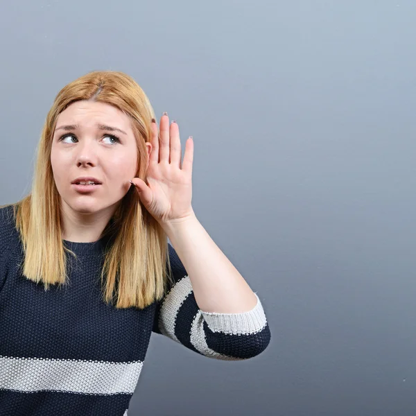 Retrato de una mujer tratando de escuchar algo contra el respaldo gris —  Fotos de Stock