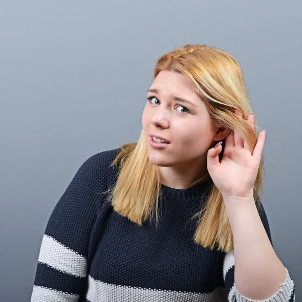 Retrato de una mujer tratando de escuchar algo contra el respaldo gris — Foto de Stock
