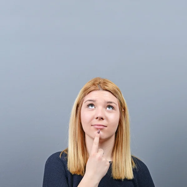 Portrait of woman coming up with an idea against gray background — Stock Photo, Image