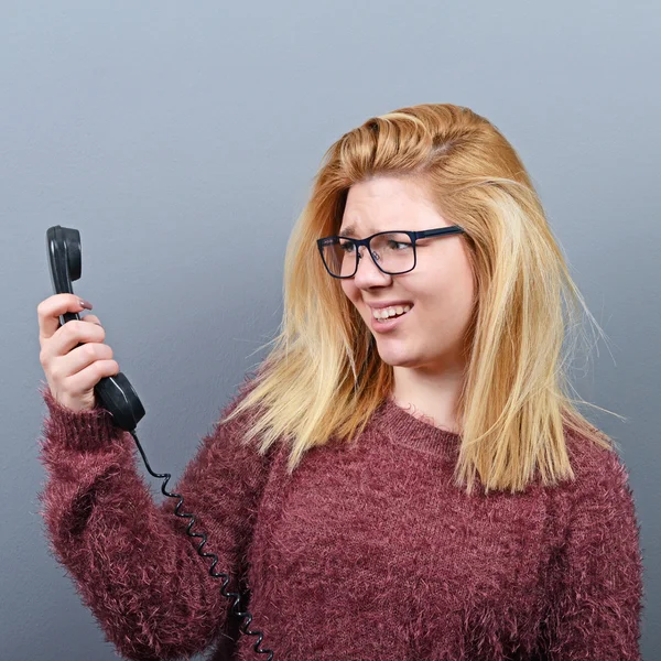 Retrato de una mujer que tiene una llamada telefónica desagradable contra el bac gris —  Fotos de Stock