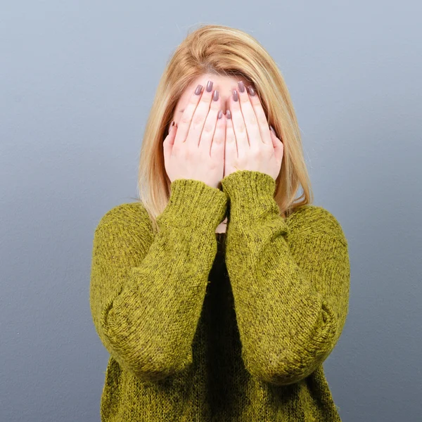 Portret van vrouw verbergt haar gezicht met beide handen tegen grijs b — Stockfoto