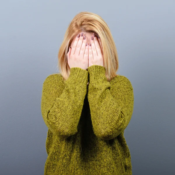 Porträt einer Frau, die ihr Gesicht mit beiden Händen vor grauen B versteckt — Stockfoto