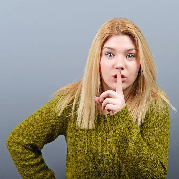 Portrait of woman holding finger over lips as silent gesture aga — Stock Photo, Image