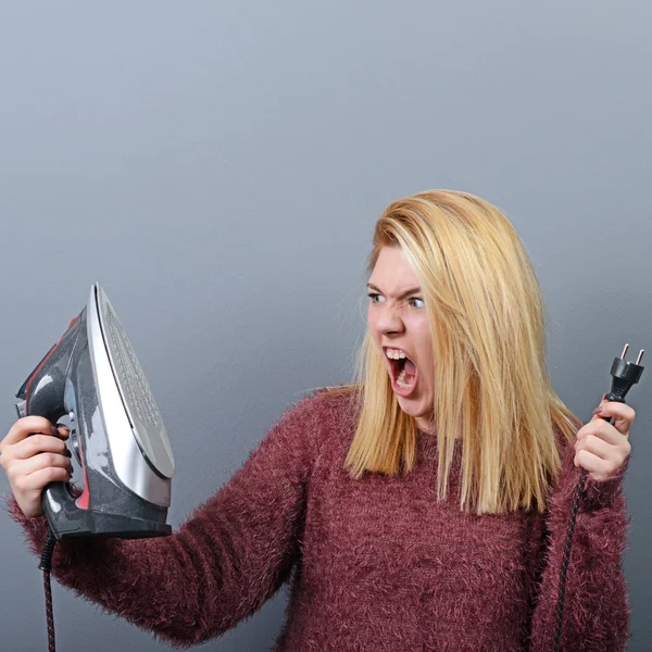 Портрет женщины, кричащей на утюг и уставшей от домашней работы — стоковое фото