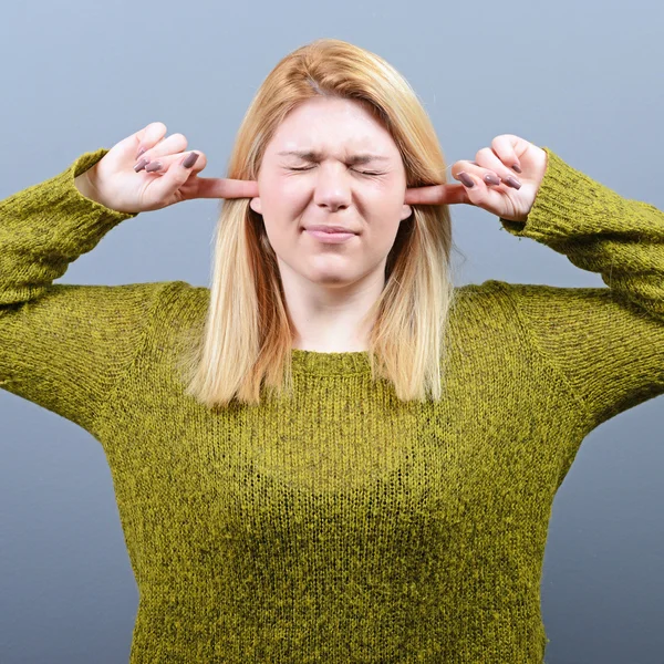 Porträt einer Frau, die vor grauem Hintergrund Ohren zupft — Stockfoto