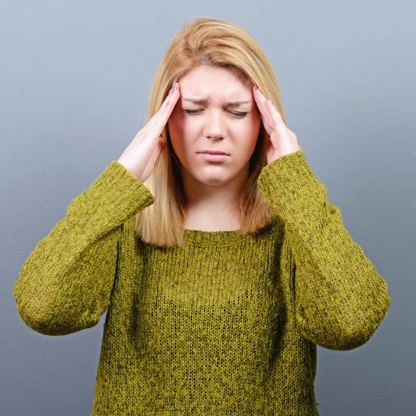 Portrait of woman with headache against gray background — Stock Photo, Image