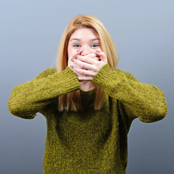 Vrouw die betrekking hebben op haar mond met handen tegen de grijze achtergrond — Stockfoto