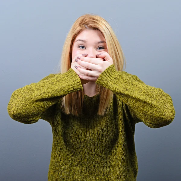 Vrouw die betrekking hebben op haar mond met handen tegen de grijze achtergrond — Stockfoto