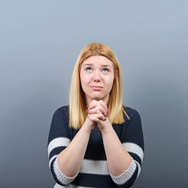 Mujer rezando por algo o suplicando misericordia contra el gris — Foto de Stock