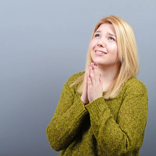 Woman praying about something or begging for mercy against gray — Stock Photo, Image