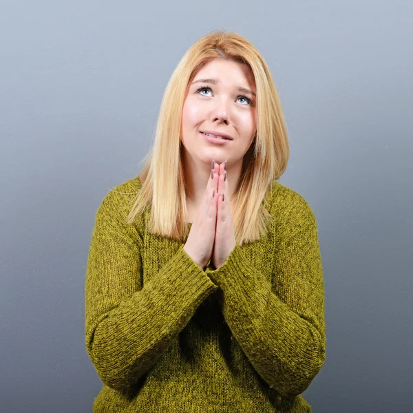 Mujer rezando por algo o suplicando misericordia contra el gris —  Fotos de Stock