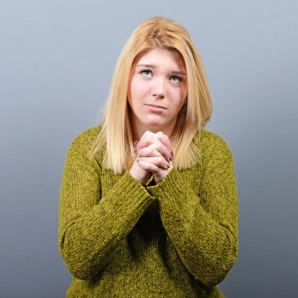 Woman praying about something or begging for mercy against gray — Stock Photo, Image