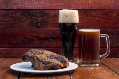 Biftek ve bira ahşap arka plan üzerinde 