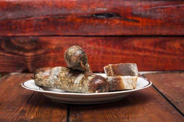 Birra e salsiccia alla griglia su sfondo di legno — Foto Stock