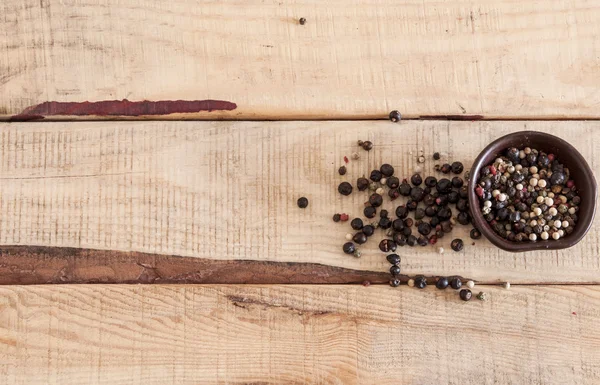 Grains de poivre entiers sur cuillères en bois — Photo