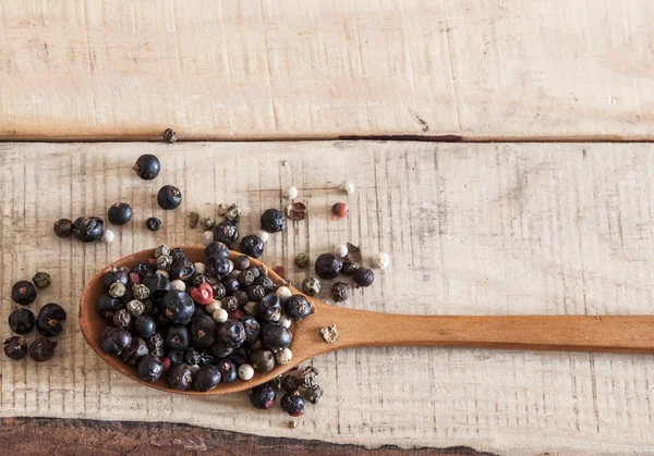 Grains de poivre entiers sur cuillères en bois — Photo