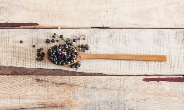 Whole peppercorns on wooden spoons — Stock Photo, Image