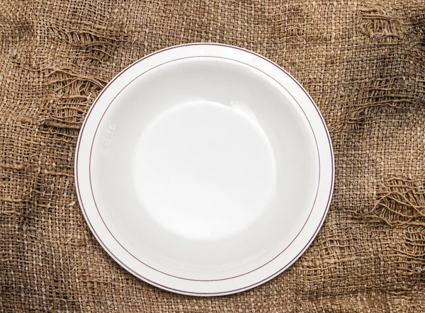 Пустая тарелка на фоне мешковины . — стоковое фото