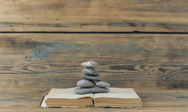 books and stack of zen stones on wood table background. Feng Shui, Balance and relaxation concept.