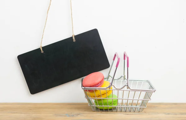 Kleiner Einkaufswagen Mit Bunten Makronen Auf Holztisch Über Weißer Wand — Stockfoto