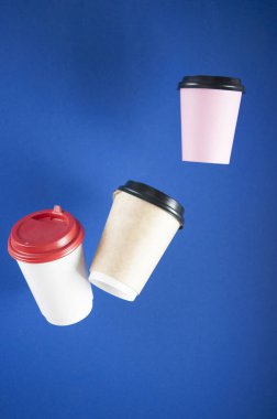 Tek kullanımlık kağıt, arka planda asılı duran kahve fincanlarıyla uçuyor. Paket kahve konsepti. Soyut arkaplan