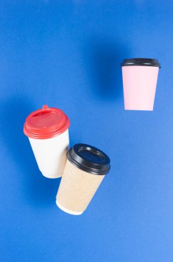 Tek kullanımlık kağıt, arka planda asılı duran kahve fincanlarıyla uçuyor. Paket kahve konsepti. Soyut arkaplan